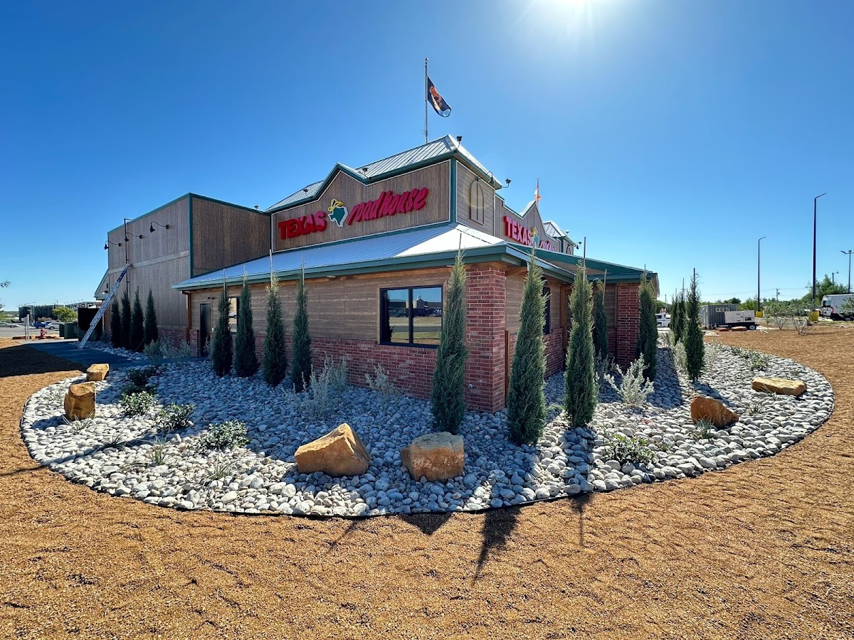 RSR Landscaping commercial install at Texas Roadhouse in Eagle Pass, with rock features, trees, and boulders