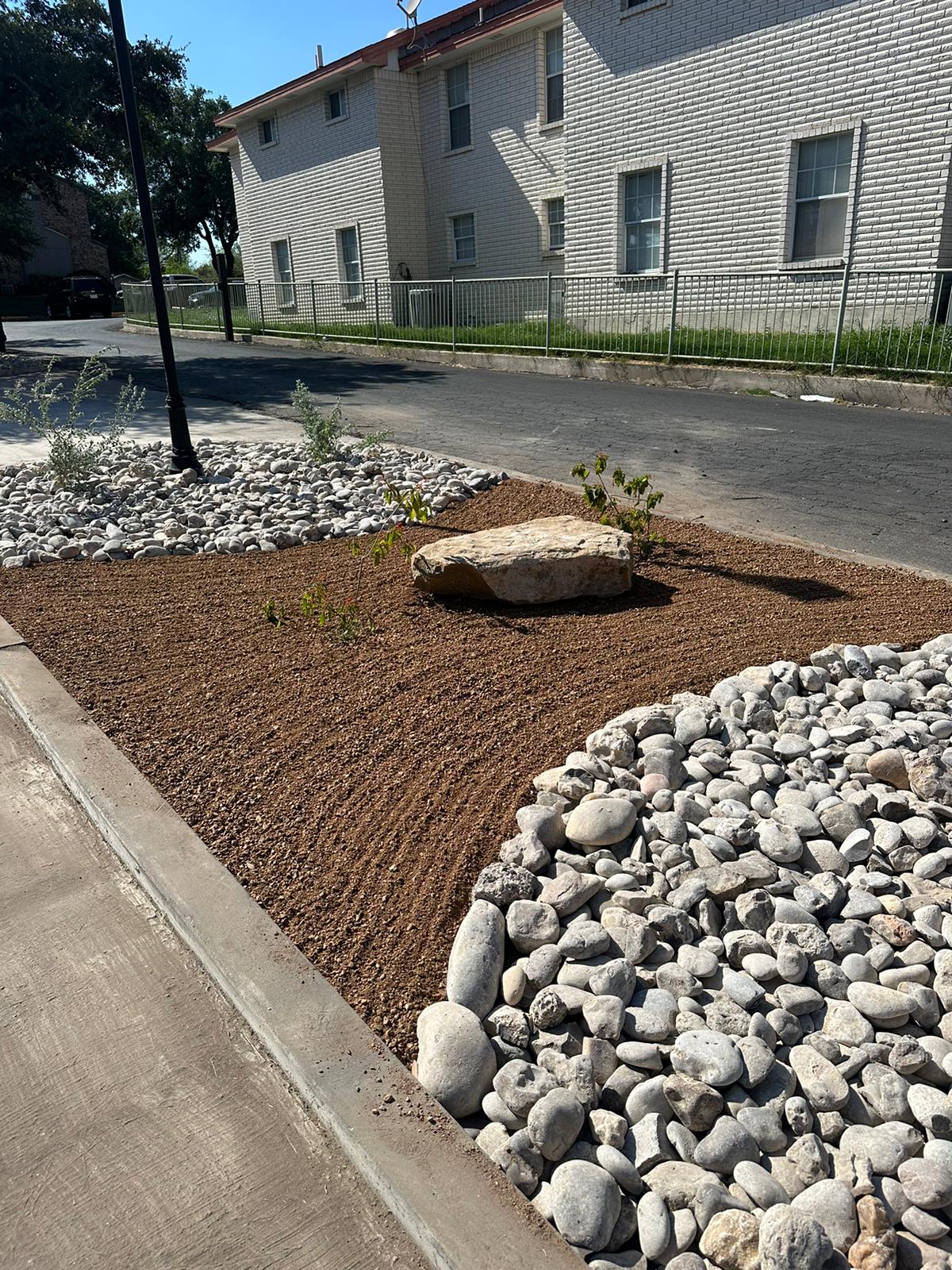 Rock and gravel ground cover with a boulder accent and river rock border