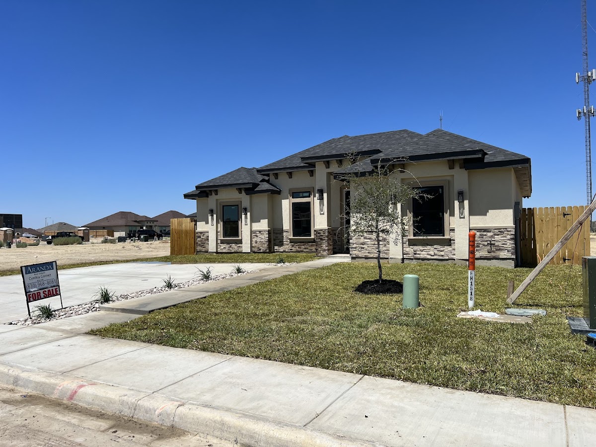 Residential new-build home with a fresh lawn installation, rock edging, and a young tree